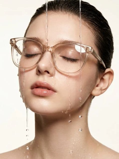 Extreme close-up beauty portrait of a woman with wet swept-back hair and translucent glasses