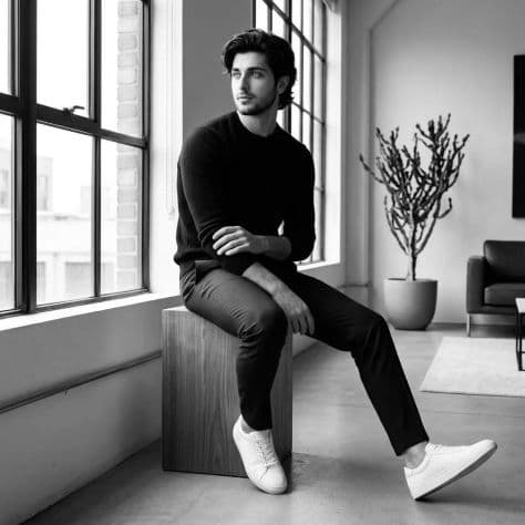 A monochrome photograph of a person relaxing on a low designer sofa in a minimalist modern loft.