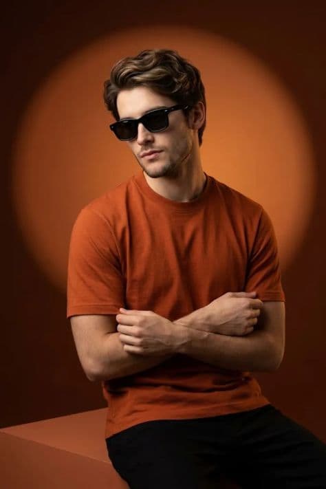A model styled in rich rust and terracotta tailored garments posing against warm studio set blocks.