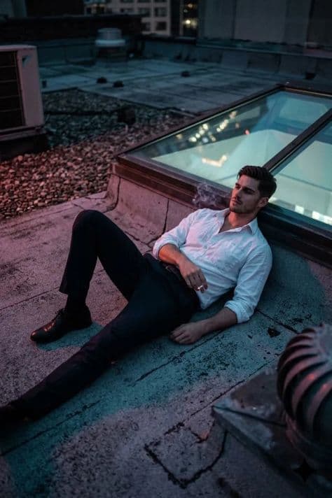A solitary figure in dark apparel on an open observation deck looking out over city lights at midnight.