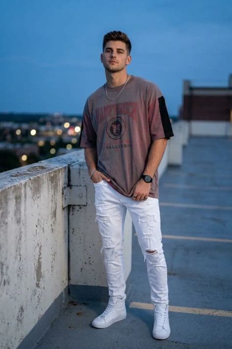 A person standing on an open rooftop concrete parking deck overlooking a glowing metropolitan skyline at blue hour.