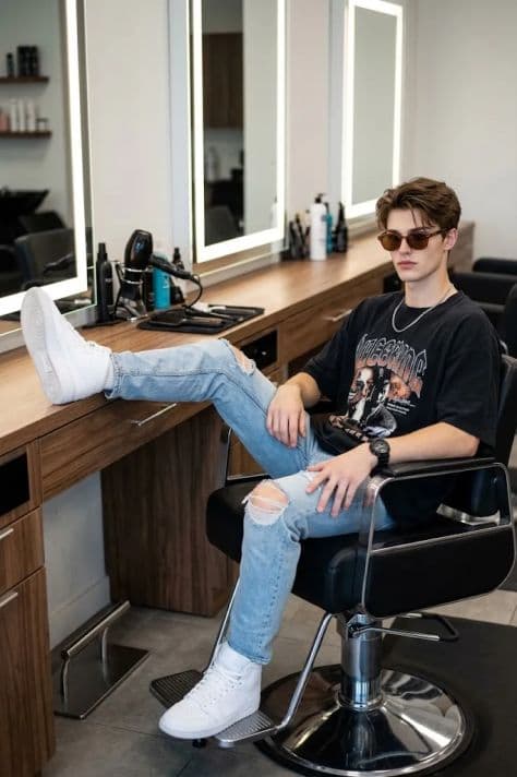 A stylish subject seated in a premium black leather styling chair inside a modern boutique salon with warm ambient lighting.
