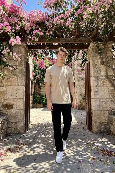 A subject walking beneath an arched pergola draped in vibrant cascading magenta bougainvillea flowers.