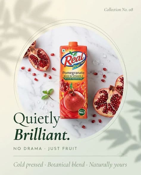 A clean fruit juice carton centered on white Italian marble with split pomegranates and clear ice chips.