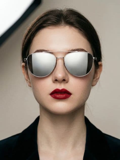 Beauty close-up of a woman with saturated deep red lips wearing oversized mirrored sunglasses