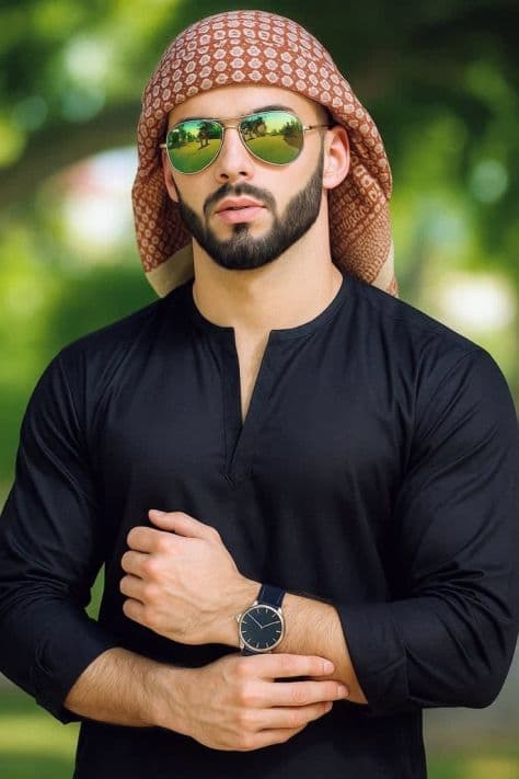 Man wearing a black kurta and traditional keffiyeh scarf posing outdoors in warm natural daylight.