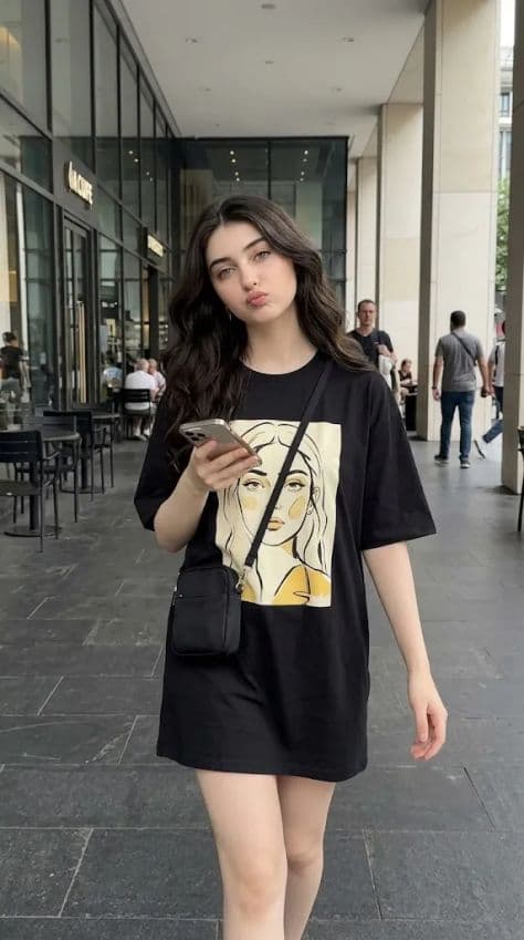 Young woman mid-stride in an oversized graphic t-shirt dress in an outdoor cafe courtyard
