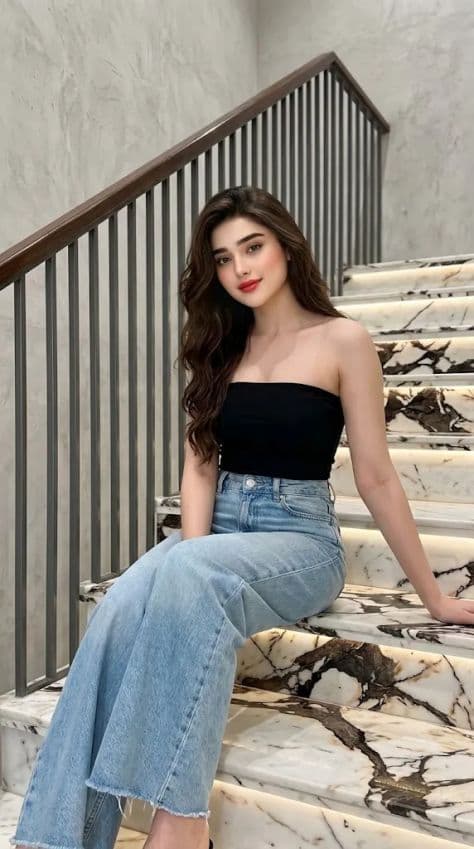 Young woman in black bandeau and wide-leg denim seated casually on elegant marble steps