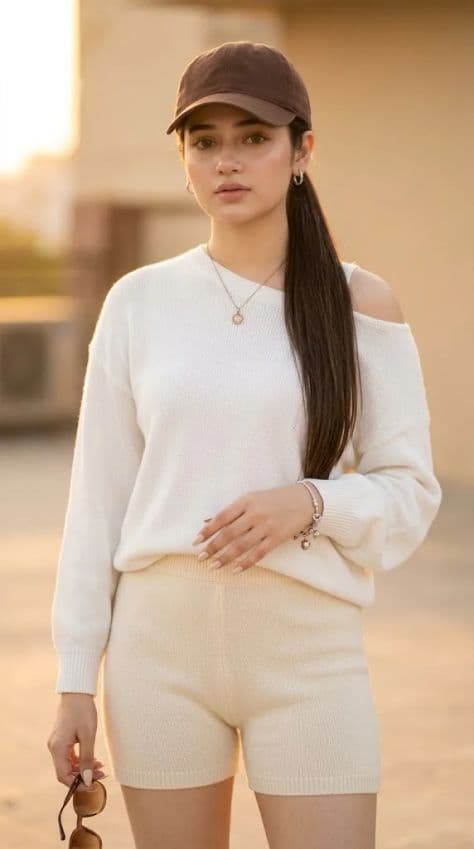 Full-body portrait of an Asian woman in cream knit sweater and shorts standing in golden sunset light