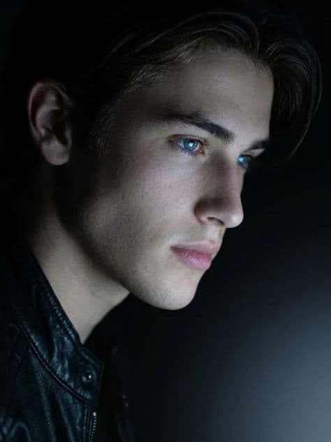 Cinematic low-angle side profile portrait of a man in a black leather jacket illuminated by cool blue light