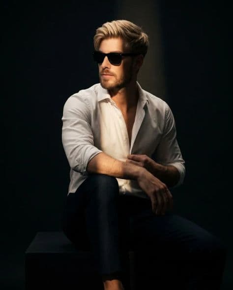 A dramatic male portrait against a pure black background with precise golden rim lighting defining his facial silhouette.