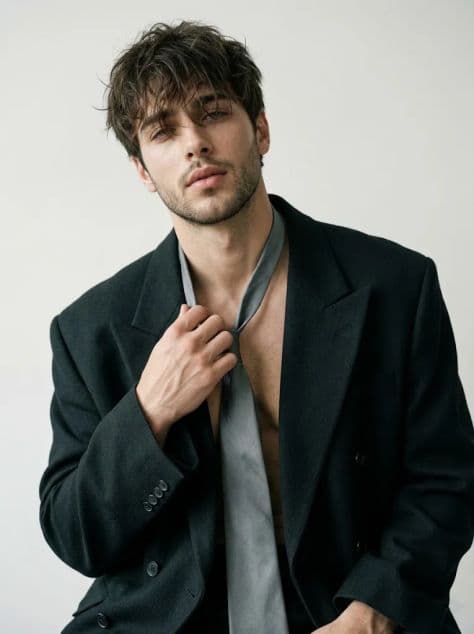 High-angle editorial fashion portrait of a muscular man wearing premium designer clothing in a studio.