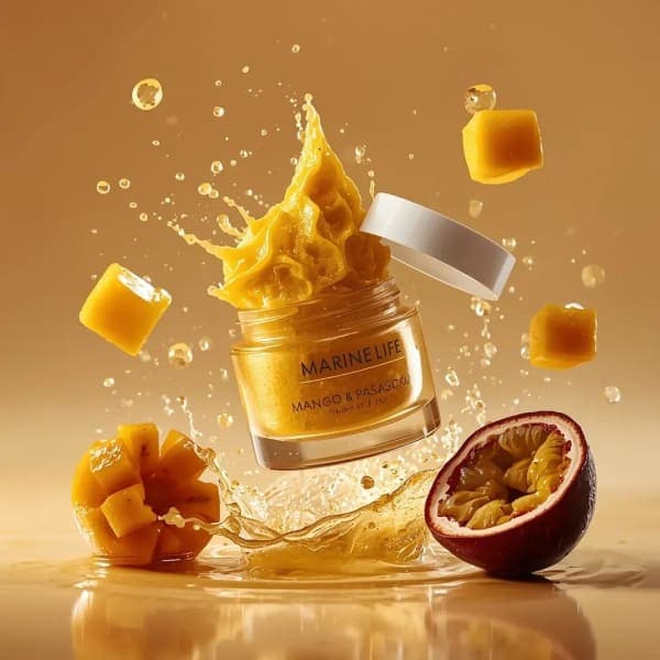 Luxury skincare scrub jar labeled MARINE LIFE exploding with mango, passionfruit, and golden scrub textures in a warm beige cinematic studio background.