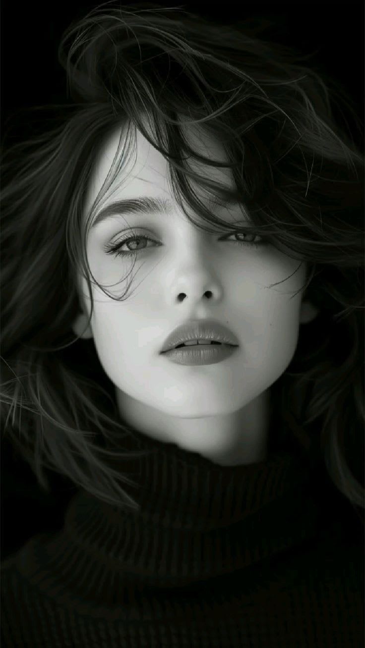 Ultra-photorealistic vertical black-and-white editorial close-up portrait of a young woman wearing a dark high-neck ribbed top, with wind-swept charcoal-black hair crossing her face, softly parted lips showing a small glimpse of teeth, direct camera gaze, dramatic monochrome lighting, and a deep black studio background.