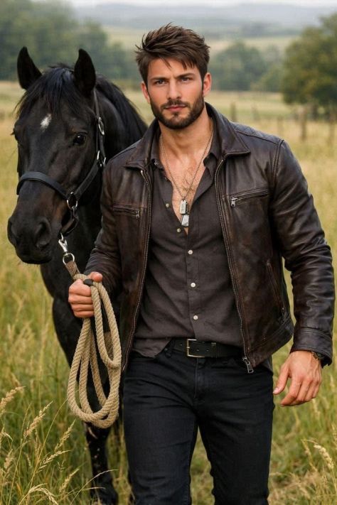 Young man in a brown leather jacket walking through a grassy countryside field while leading a black horse, captured in a natural editorial ranch portrait.