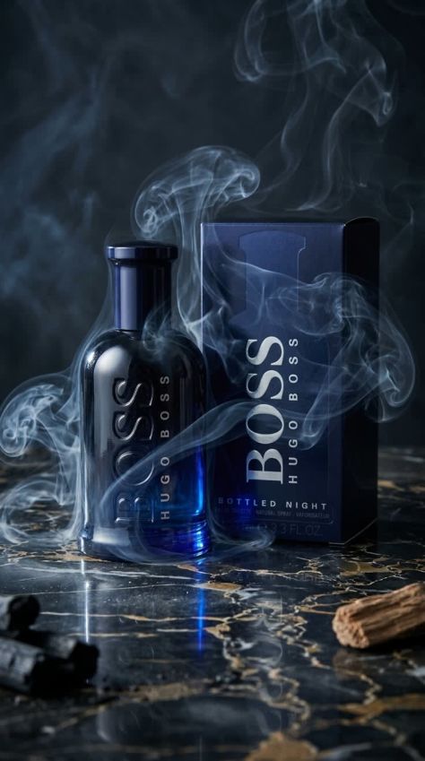Dark luxury commercial fragrance hero shot featuring a Boss Bottled Night bottle and matching retail box on glossy black marble, surrounded by moody blue smoke, reflective highlights, charcoal props, and premium editorial lighting.